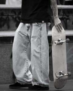 Stylish young skater holding skateboard, showcasing urban street fashion.